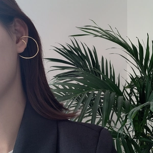 Detail of minimalist gold double hoop ear cuff worn on model with a natural background