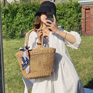 Handwoven straw tote bag with decorative scarf in outdoor garden setting for summer vacations
