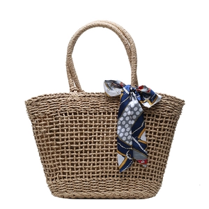 Handmade straw tote bag with blue polka dot silk scarf accessory on a white background