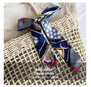 Detail of nautical print silk scarf tied as a decoration on a straw handbag handle