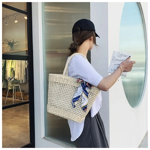 Detail of hand-woven straw shoulder bag with elegant blue polka dot scarf decoration