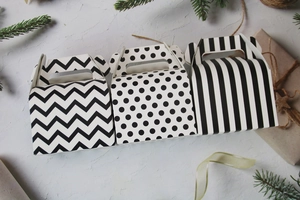 Three Halloween cake boxes with black wave, dot, and stripe patterns on a festive surface