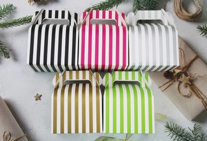 Close-up of colorful striped Halloween cake gift boxes with handles in festive setting