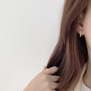 Detail of square gold earrings and double layer ring on model for daily wear look