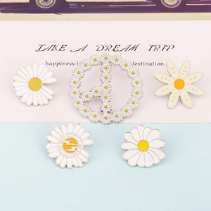 Detailed close-up of a five-piece set of white and yellow daisy enamel pins on blue background