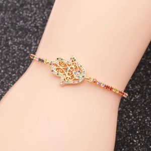 Bracelet main de Fatma dorée avec zircons colorés porté sur le poignet d'un modèle