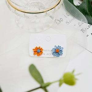 Detail of asymmetric daisy earrings with blue and orange petals on 925 silver posts