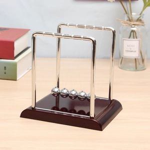 Close-up of Newton's cradle featuring silver metal balls and a dark wooden base