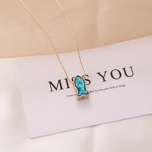 Macro shot of a golden fish-shaped necklace pendant with deep blue opal inlay details