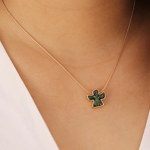 Close-up of golden necklace featuring a green angel pendant on a female model neck