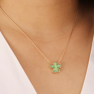 Close-up of a gold angel pendant with green opal stone worn on a delicate gold chain
