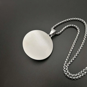 Detailed close-up of a silver-tone round brushed metal pendant on a minimalist square link chain