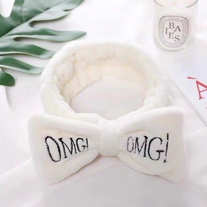 White coral fleece OMG! headband for makeup and face washing with a plush bow design