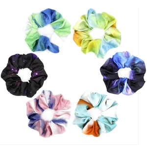 Detail of six colorful tie-dye fabric scrunchies in galaxy and gradient patterns