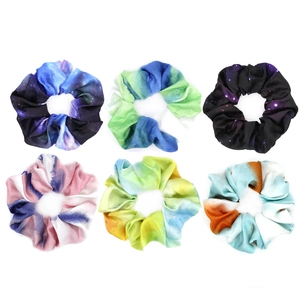 Close-up of colorful tie-dye and nebula print fabric scrunchies in various artistic patterns
