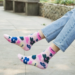 Pink mid-calf cotton socks featuring colorful floral patterns on a stone step background