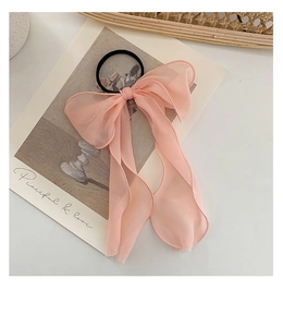 Detail view of a pink lace oversized bow hair tie with chiffon ribbons and elastic band