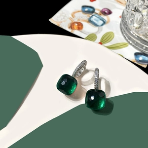 Macro shot of dark green square crystal earrings with pavé stones on white tray