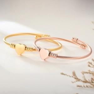 Close-up of gold and rose gold stainless steel cable bracelets with heart pendants