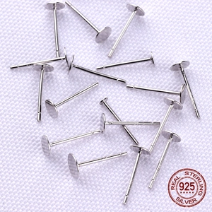 Scattered S925 sterling silver flat head earring posts on white textured background