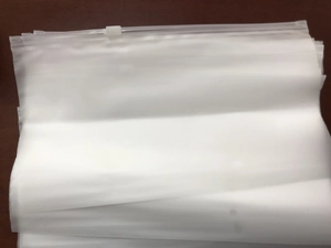 Close-up of stacked translucent frosted zipper storage bags on a dark wooden surface