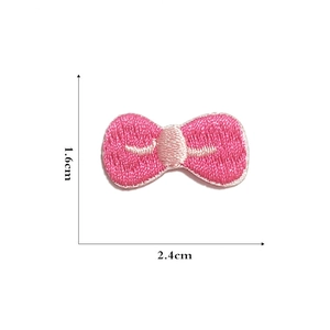 Detail of a pink embroidered bow patch showing 1.6cm x 2.4cm dimensions for DIY crafts