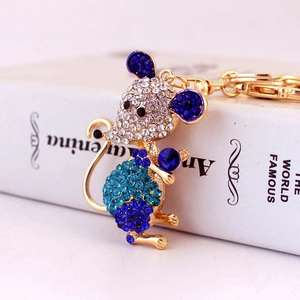 Golden mouse keychain with white and blue rhinestones on a white book background