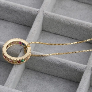 Golden round necklace with colorful square gemstones and box chain in a velvet box