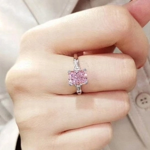 Detail of pink square-cut gemstone ring with side baguette stones on model hand