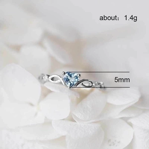 Silver-colored heart-shaped ring with light blue gemstone and twisted band design