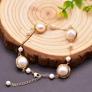 Detail of handmade freshwater pearl bracelet with gold wire wrapping on a wooden background