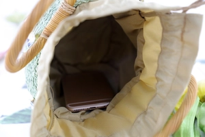 Internal view of green straw bucket bag showing fabric lining and spacious capacity
