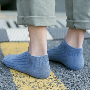 Light blue low-cut cotton ankle socks with vertical stripe texture worn on asphalt road