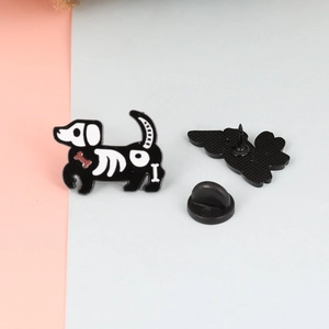 Detail showing cartoon skeleton cat enamel pin with a black rubber clutch on the back