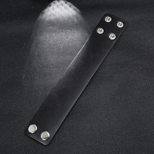 Punk black leather wristband with adjustable silver metal snaps on dark background
