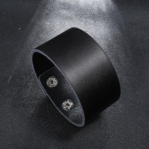 Detail of wide black leather punk bracelet showing two metal snap buttons and texture