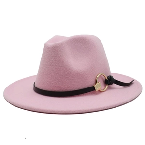 Detail of pink fedora hat featuring black leather band and golden metal ring ornament