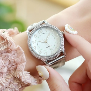 Close-up of silver mesh strap quartz watch with rhinestone bezel on female wrist