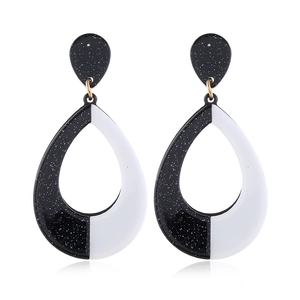 Macro view of geometric black and white acrylic drop earrings with gold metal hooks