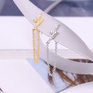 Macro view of lightning bolt stud earrings with zircon inlay and hanging chain tassels