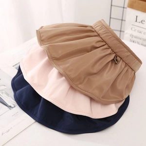 Detail of pleated sun visors in brown, pink, and navy blue with metal buckle accents