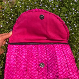 Dettaglio della pochette in paglia fucsia con trama intrecciata e chiusura magnetica