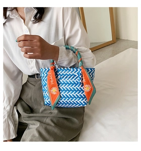 Detailed blue and white hand-woven tote bag with decorative orange peace scarf handle