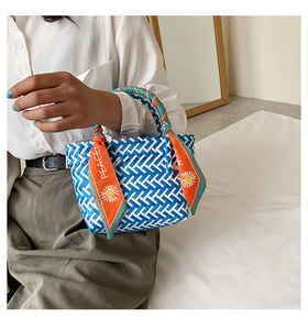 Détail d'un sac cabas tissé bleu et blanc avec un foulard décoratif en soie orange