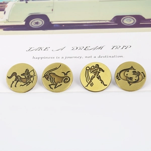 Close-up of four vintage bronze zodiac badges with brushed metal texture on a white surface