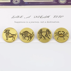 Close-up of four bronze zodiac brooches including Aries and Taurus on a white card