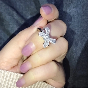 Elegant silver bow ring with square and round diamonds shown on model's hand