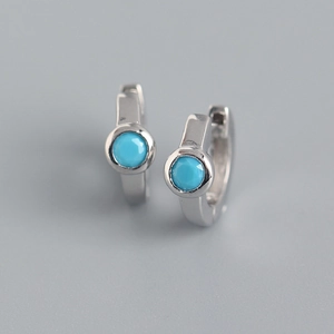 Macro view of S925 silver huggie earrings with round turquoise zircon stone inlay