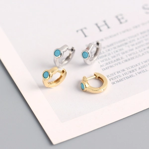 Gold and silver S925 sterling silver hoop earrings with turquoise stones on paper