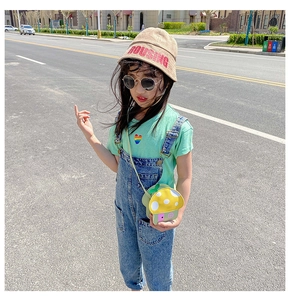 Outdoor street style view of yellow mushroom crossbody bag and beige canvas fisherman hat